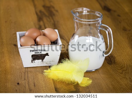 Glass Jug of Milk with wooden box of eggs