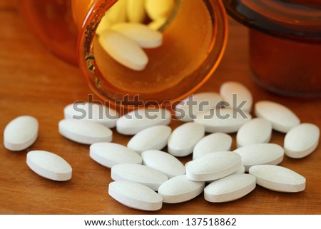 White pills next to brown vintage medicine bottle