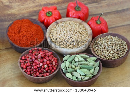 Mixed spices and round hot peppers on wooden background