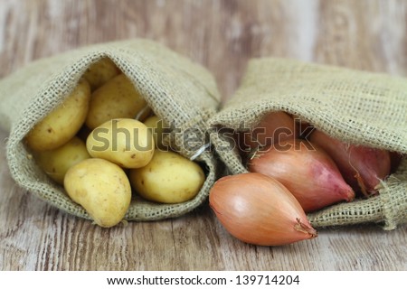 New potatoes and shallots in jute bags, close up