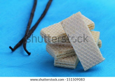 Vanilla wafers on blue background and vanilla sticks