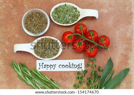 Happy cooking card with cherry tomatoes, fresh and dried herbs on terracotta surface