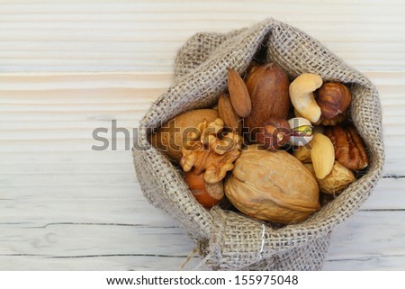 Selection of nuts in jute bag on wooden surface with copy space