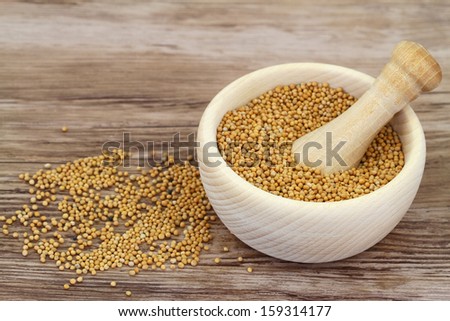 Mustard seeds in wooden mortar and mustard in white bowl with copy space