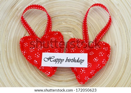 Happy birthday card on two red knitted hearts