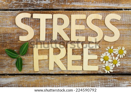 Stress free written with wooden letters on rustic wooden surface with fresh chamomile flowers
