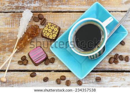 Coffee, sugar sticks and chocolates on rustic wooden surface