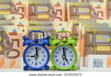 Miniature clocks showing nine and five o\'clock with banknotes in the background, concept of a nine to five job