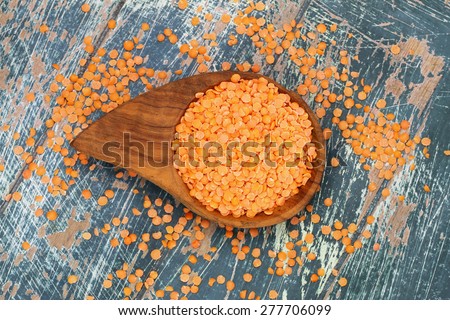 Uncooked red lentils in bamboo dish on rustic surface