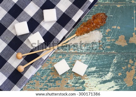 White sugar cubes and white and brown sugar sticks on rustic wooden surface