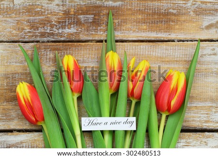Have a nice day card with red and yellow tulips on rustic wood