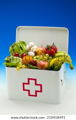 Healthy food. First aid box filled with fresh fruits and vegetables on blue background.