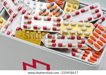 Open first aid box filled with pills. White background. Drugs abuse.