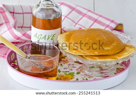 Agave syrup and pancakes.. Alternative sweetener to sugar. Selective focus. White background. Taken in daylight.