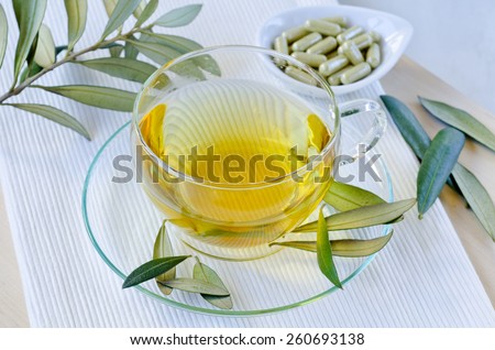 Olive leaf infusion and olive leaf extract capsules. Alternative medicine.  Selective focus. Taken in daylight.