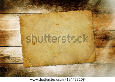 Old torn card on the shabby wooden background