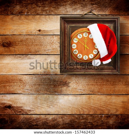Santa Claus hat on New Year\'s night on the old clock showing twelve o\'clock on the wooden background