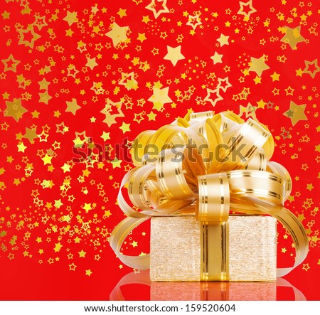 Gift box in gold wrapping paper on a beautiful red abstract background
