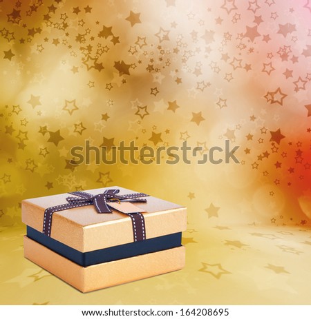Beautiful Gift gold box with bow on the abstract star background with bokeh effect