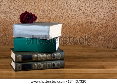 Pile of old books with rose on the beautiful wooden table