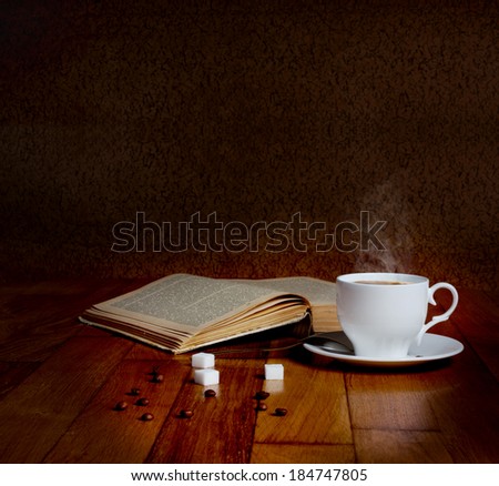 Hot cup of fresh coffee on the wooden table and a stack of books to read