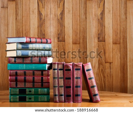 Richly decorated volumes of books with a gold lettering on the beautiful wooden shelf