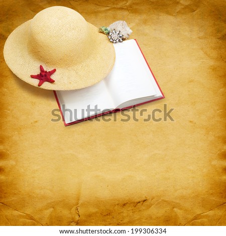 Straw hat with book and red starfish on shabby paper background