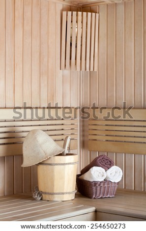 Traditional wooden sauna for relaxation with bucket of water and set of clean towels