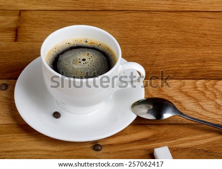 Hot fresh coffee in a white cup with sugar on wooden table