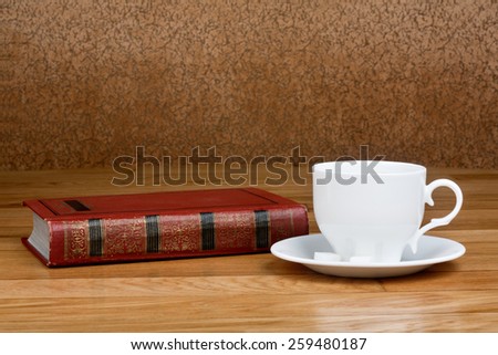 Hot cup of fresh coffee on the wooden table and a stack of books to read