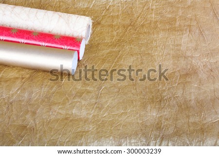 Rolls of multicolored wrapping paper with streamer for gifts on gold abstract background. View from above with copy space