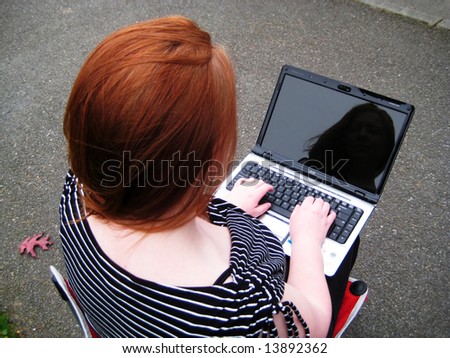 Woman and her Reflection on Laptop as she sends her email across the internet with wireless technology.