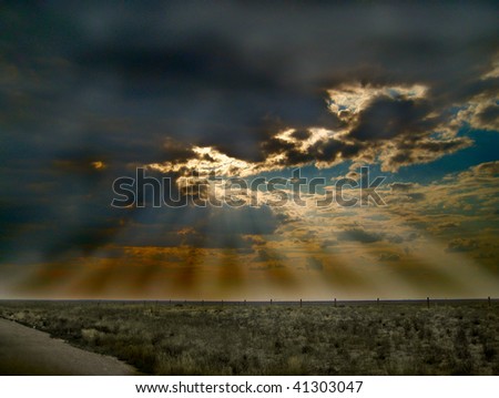 Storm on the Horizon has Rays of Hope shining down across a rural countryside with a barbed wire fence.