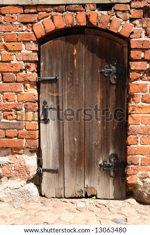 An old, rotten door in a brick wall
