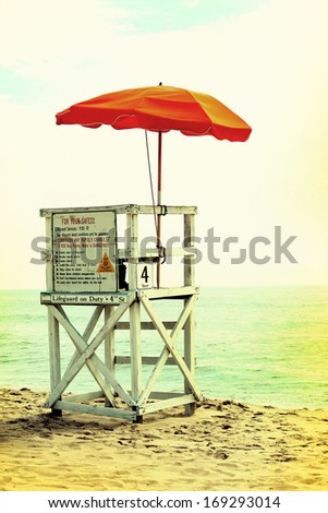 An empty lifeguard tower overlooking the ocean at the beach. Vintage photograph effects.