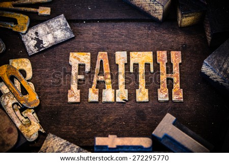 The word faith written in rusted metal letters surrounded by vintage wooden and metal letterpress type.