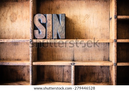 The word SIN written in vintage wooden letterpress type in a wooden type drawer.