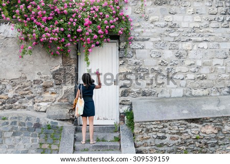 PARIS-JUNE 2: An unknown young woman picks a rose from a garden wall on June 2, 2009. As a top business and cultural center, Paris is one of the most visited cities in the world.
