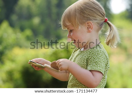 A three year old girl plays with her mother\'s powder compact
