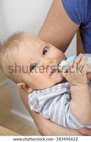Seven month old baby boy bottle feeding in his mother's arms.