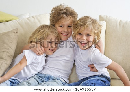 Three brothers hugging and playing on the sofa