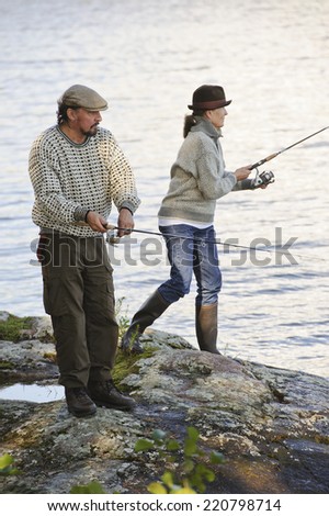 Senior couple fishing from the lake shore. Focus is on the man