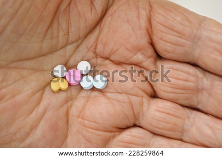 Variety of pills in the wrinkled palm of an eighty eight year old man.