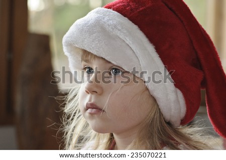 Four year old girl with a Christmas elf hat is looking off camera