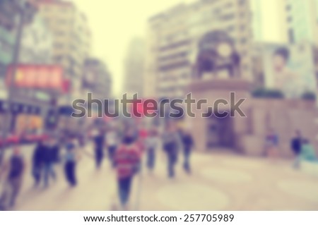 Blurred city background suitable as a background for text. Designed to work with most text colors including white. Artistic intent with filters and desaturation. Pedestrians. High rise buildings