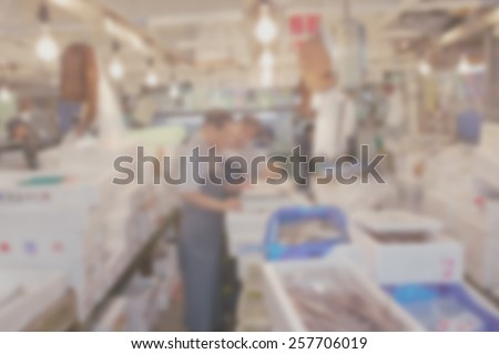 Blurred background of wholesale market. Suitable for use with text of most colors including white. Artistic intent with filters and desaturation. People at work in market surroundings