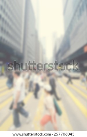 Blurred city background suitable as a background for text. Designed to work with most text colors including white. Artistic intent with filters and desaturation. Pedestrians crossing among skyscrapers