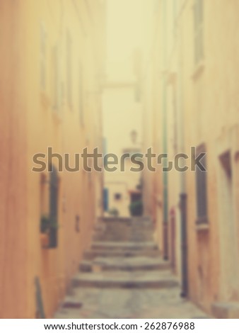 Blurred background of narrow European street with steps. Designed to work with text overlays including the text colour white. Artistic intent with filters and desaturation.