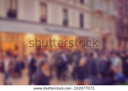 Blurred background of crowds in street outside cafe. Designed to work with text overlays including the text colour white. Artistic intent with filters and desaturation.