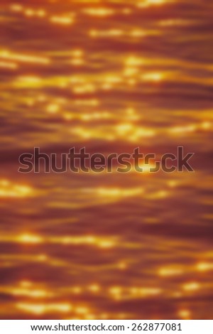 Blurred background of sparkling golden light reflecting from the sea. Designed to work with text overlays including the text colour white. Artistic intent with filters and desaturation.